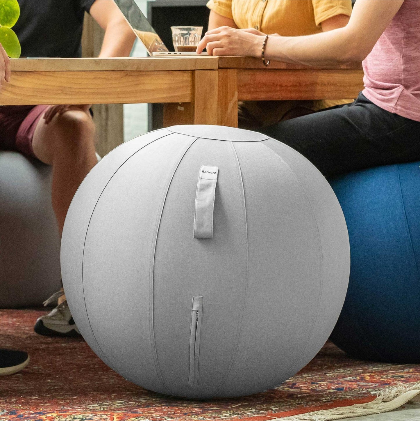 Mensen zitten samen aan een tafel met een linnen zitbal, een moment van samenzijn en plezier.