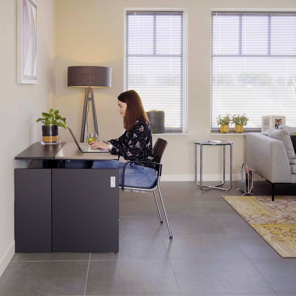 Vrouw achter een bureau in een kantoor, met een stijlvolle HomeFit thuiswerkplek.